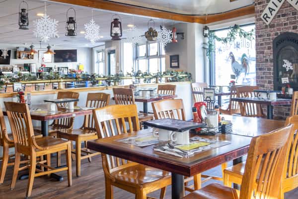 Cozy restaurant dining area decorated for the holidays with hanging snowflakes, lanterns, and festive greenery.