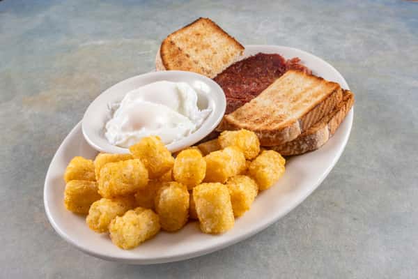 This hearty breakfast plate features poached eggs, crispy tater tots, toasted white bread, and a slice of corned beef hash.