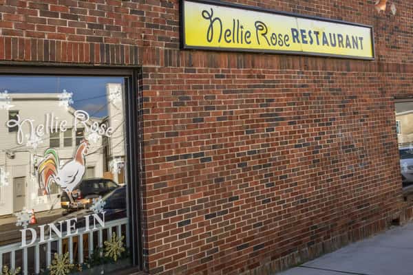 Exterior of Nellie Rose Restaurant with a painted rooster, snowflake decorations, and "DINE IN" lettering on the window.