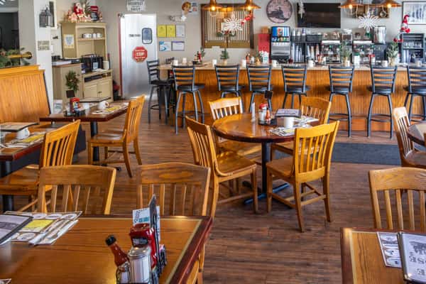 Warm and inviting diner interior with wood furnishings, counter seating, and festive holiday decorations throughout the space.