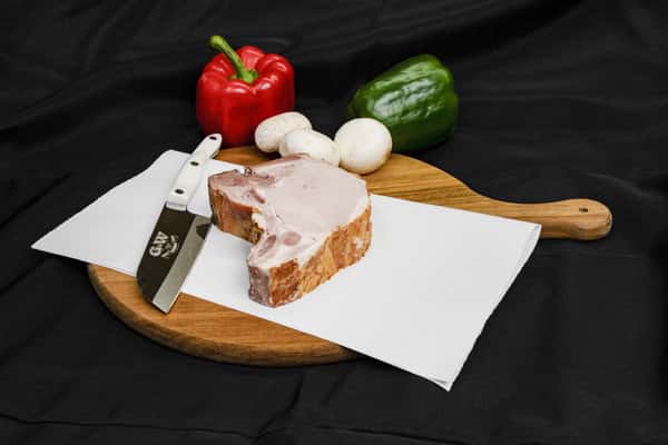 smoked pork chop on butcher paper with knife and fresh vegetables on cutting board