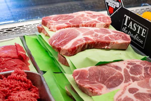 raw pork steaks displayed on green trays in deli case at G&W Sandwiches