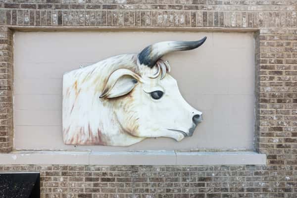 decorative cow head sculpture mounted on exterior brick wall at G&W Sausage Company