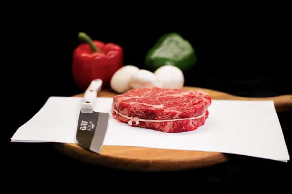 thick cut raw beef filet on white surface showing marbling and freshness