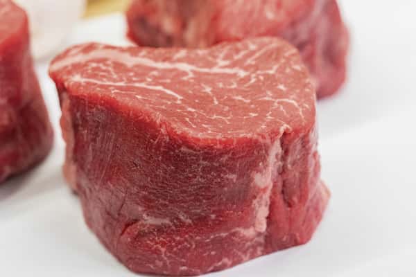 thick cut raw beef filet showcasing marbling and freshness on white surface
