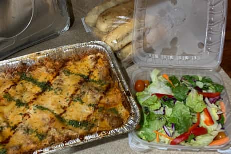 A tray of chicken casserole and a salad to go