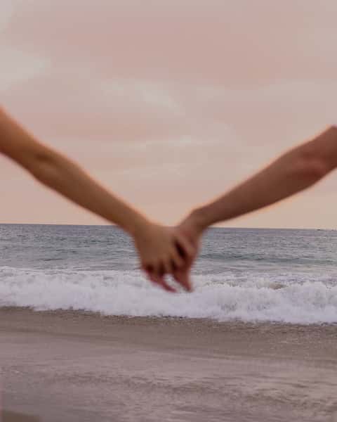 couple holding hands at the ocean