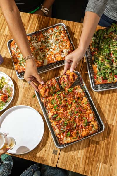 Hands grabbing pizza