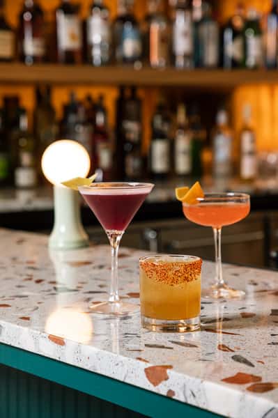 Cocktails on bar with bottles in the background