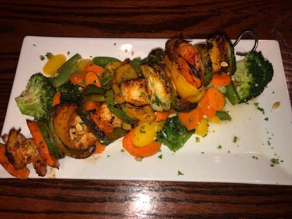 shrimp and vegetable kabobs on a bed of more vegetables