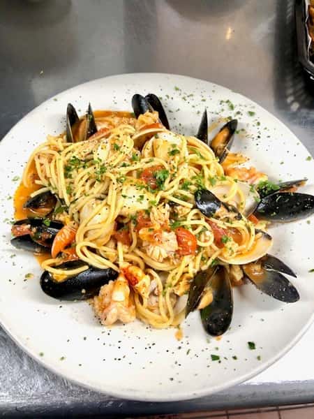 spaghetti with shrimp, mussels, clams, scallops and tomatoes with parsley as a garnish