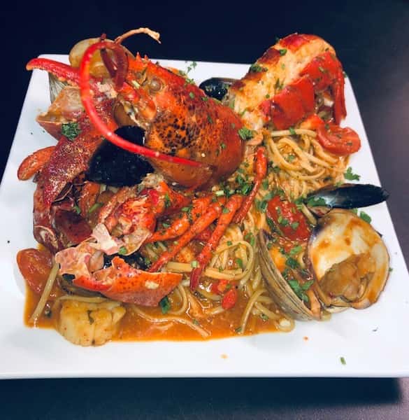 seafood entree with clams, mussels, shrimp and tomatoes around a whole lobster
