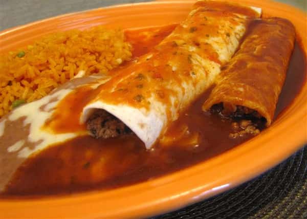 Enchiladas topped with red sauce and melted cheese served with rice