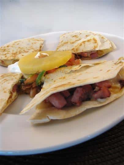 Quesadilla cut up in triangles and served with pico de gallo topped with a pineapple slice