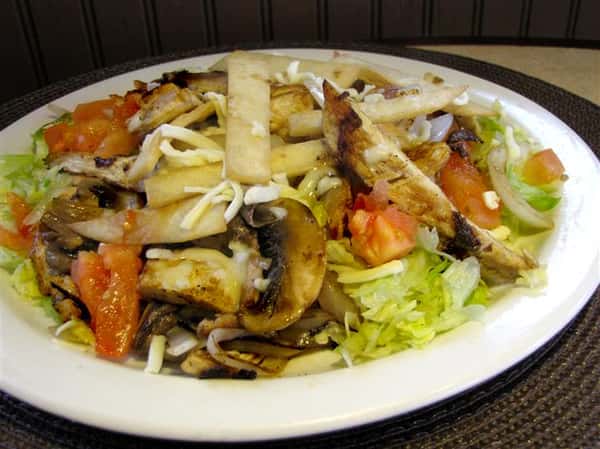 Chicken tossed salad with lettuce, tomatoes, onion and shredded cheese