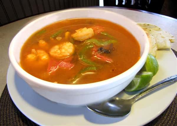 Seafood soup served in a bowl with a lime wedge