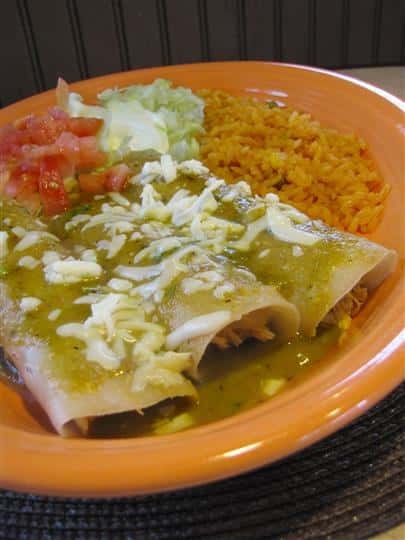Three enchiladas served with green sauce and sides of pico de gallo, sour cream and rice