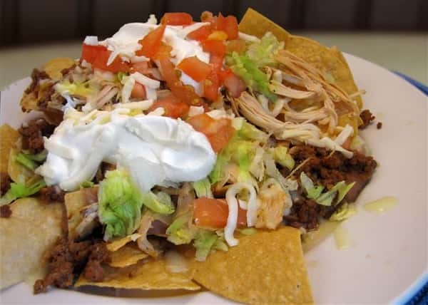 Fajita dish served with tortilla chips shredded lettuce, tomato and onion and topped with sour cream