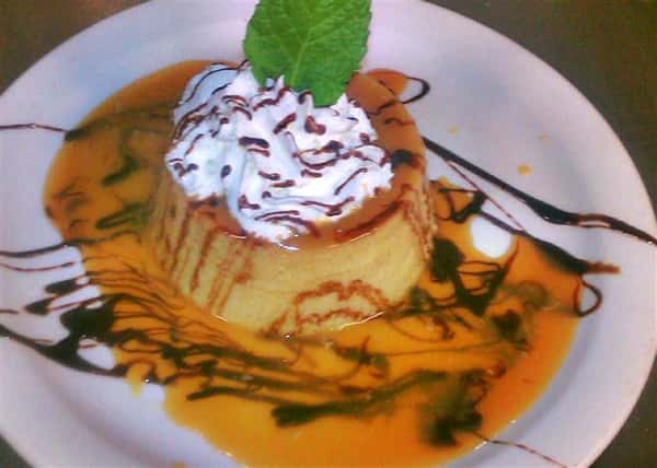 Mexican flan served with whipped cream and topped with syrup and a mint leaf
