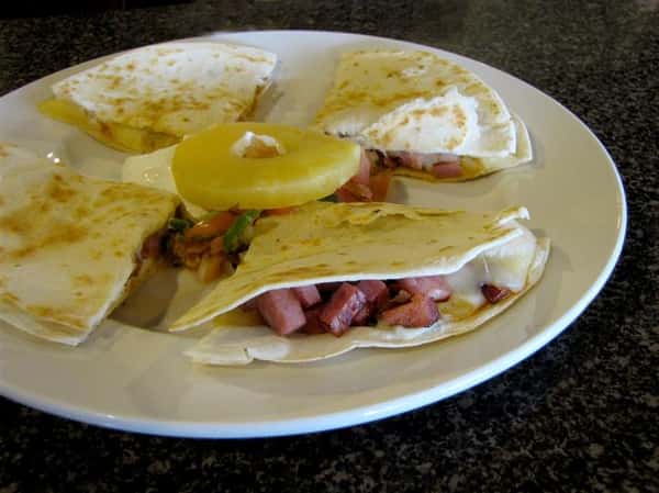 Quesadilla cut up in triangles and served with pico de gallo topped with a pineapple slice