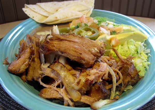 Pork dish served with grilled onions, shredded lettuce, tomato and tortilla chips
