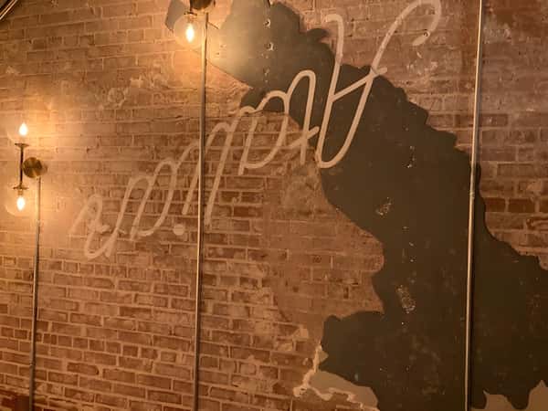 Brick wall with a stylized map outline and illuminated script sign reading "Good Spot."