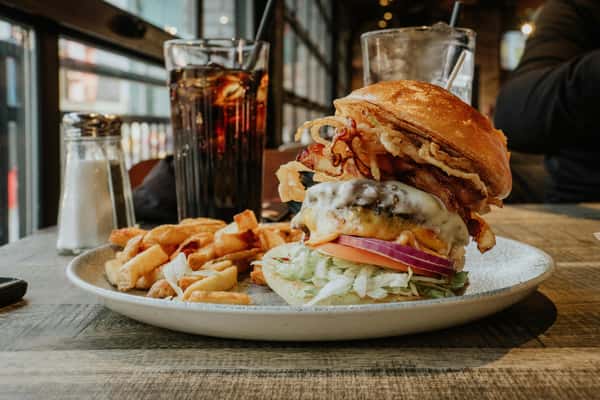 Delicious gourmet burger with fries and cola in a Niagara Falls restaurant setting.