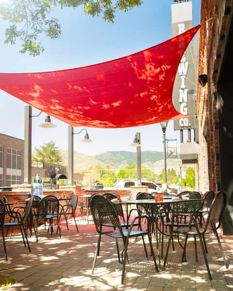 Carson City Patio with red shade tent and black tables and chairs on a sunny day.