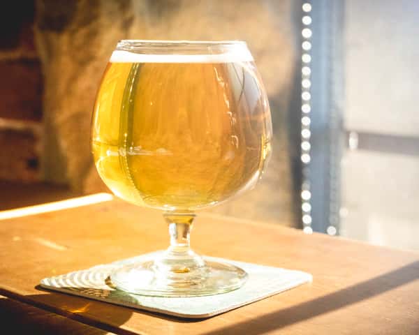 Pint of leave no trace lager in the sun on a wooden table.