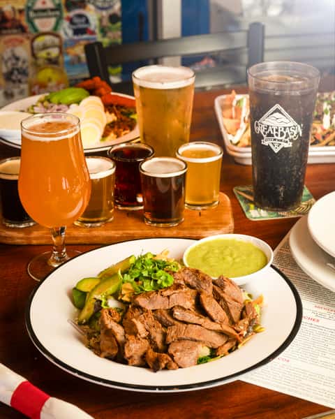 steak salad next to a couple pints of beer, coca cola, and beer flight with five beers.