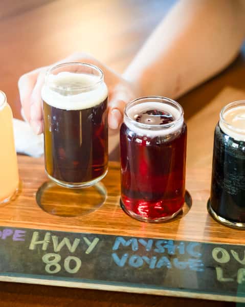 Flight of four beers with a hand holding the taster of highway 80