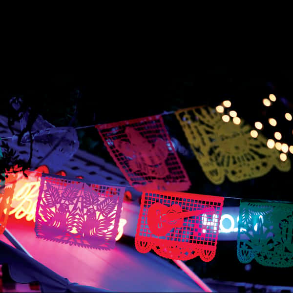 Colorful papel picado banners glowing under neon lights, creating a festive Mexican restaurant atmosphere at night.