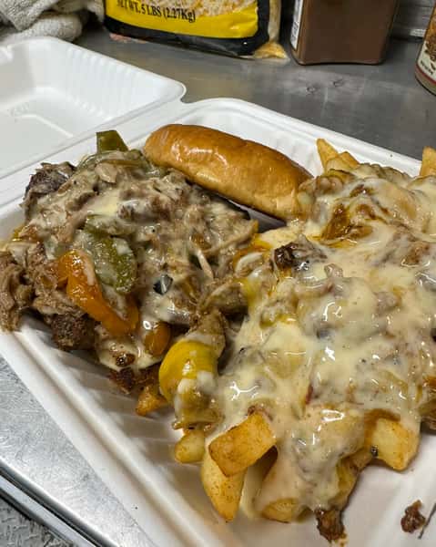 Philly cheesesteak with grilled peppers and onions, served with cheesy loaded fries and a toasted hoagie bun.