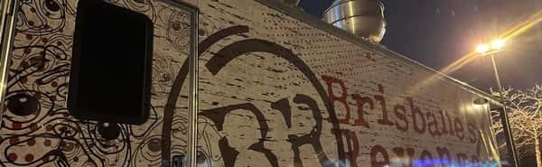 Close-up of Brisbane's Revenge food truck at night, showing pug artwork, logo, and part of the name in red letters under streetlight glow.