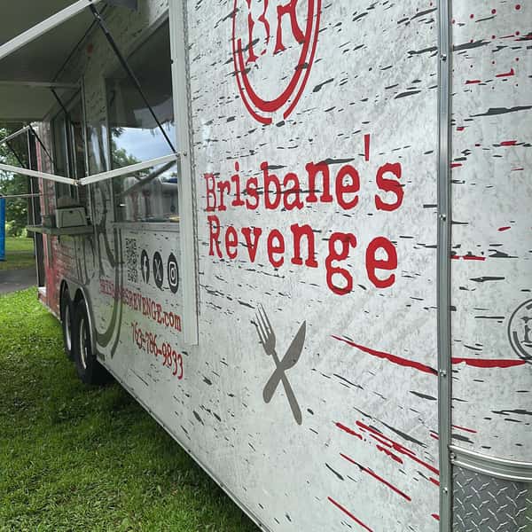 Side view of the Brisbane's Revenge food truck parked on grass with its service window open and bold red branding displayed.