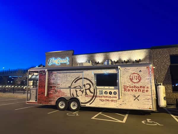 Brisbane's Revenge food truck parked outside Elm Creek restaurant under a deep blue evening sky, lights illuminating the scene.
