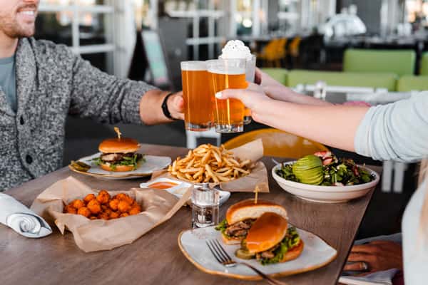 Cheers with two beers and a shake, over burgers, fries, salads, and tater tots