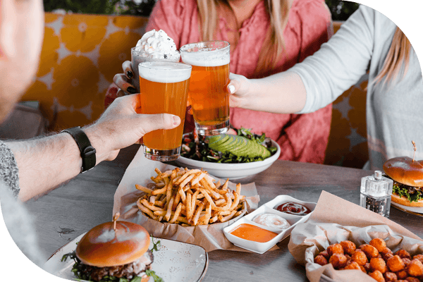 Cheers with two beers and a shake, above a Truland burger, fries, tots, and salad