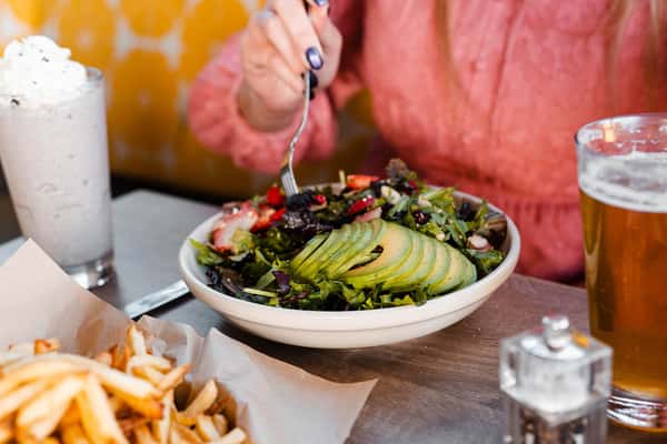 Person eating a Truland salad with avocado