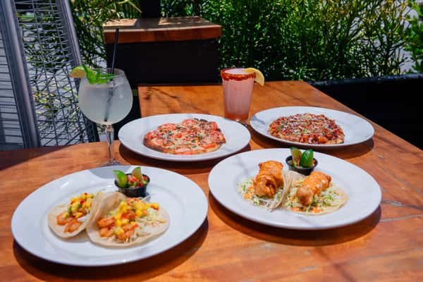 Landscape photo of the fish tacos and shrimp tacos with the Margherita and the BBQ Chicken flatbread and the spritz and frozen cocktails