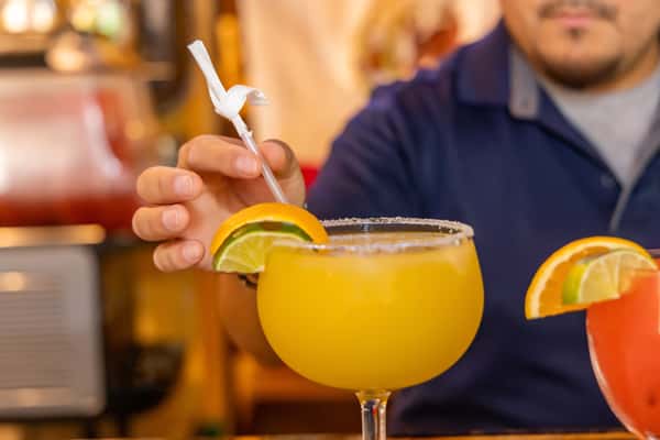 A refreshing mango margarita served in a salt-rimmed goblet, garnished with lime and orange slices — the perfect blend of sweet, tangy, and citrusy flavors.
