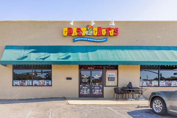 Front exterior of Crazy Cactus Mexican Restaurant with green awning, colorful signage, and outdoor patio seating.