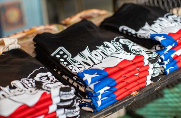 A stack of black Gas Monkey t-shirts featuring a logo design with a monkey and a red, white, and blue flag motif.
