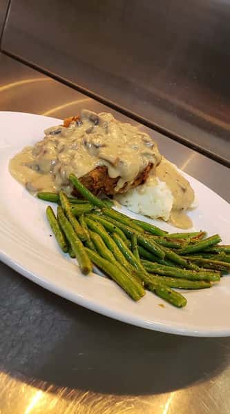 Fried chicken topped with mushroom gravy with a side of green beans