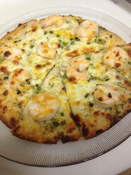 large cheese pizza with herbs on a wooden board