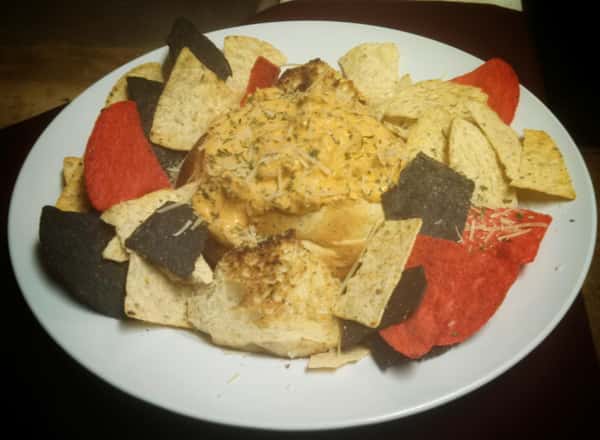 plate of tortilla chips with dip in the center of the plate