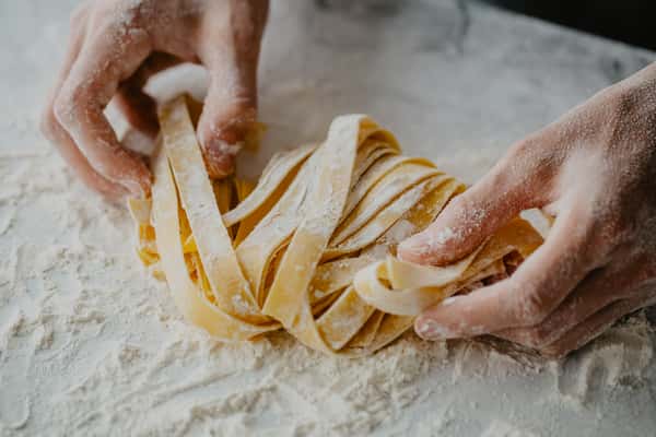 Hands holding freshly made strips of pasta