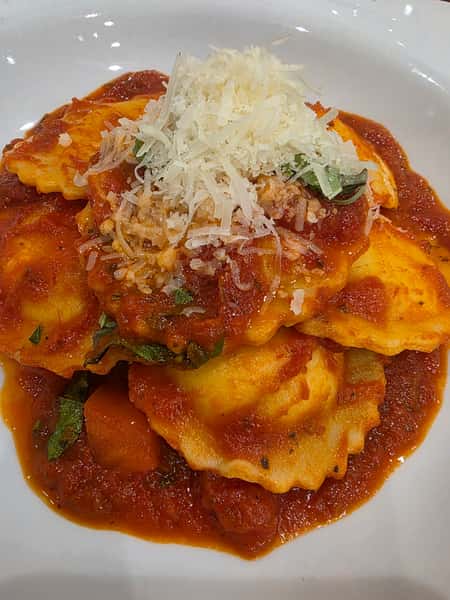 Cheese ravioli in tomato sauce topped with shredded parmesan and fresh basil