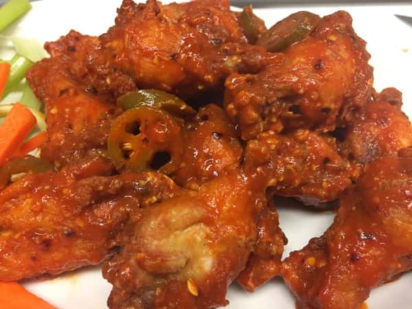 a plate of wings with jalapenos on top