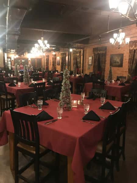 inside view of the restaurant with multiple tables and mini christmas trees on the table as centerpieces
